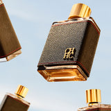 Perfume bottle with gold cap and textured brown body on a light blue background